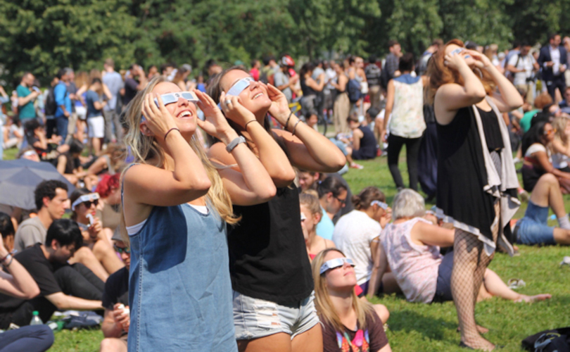A crowd looking up at the sky with eclipse glasses.