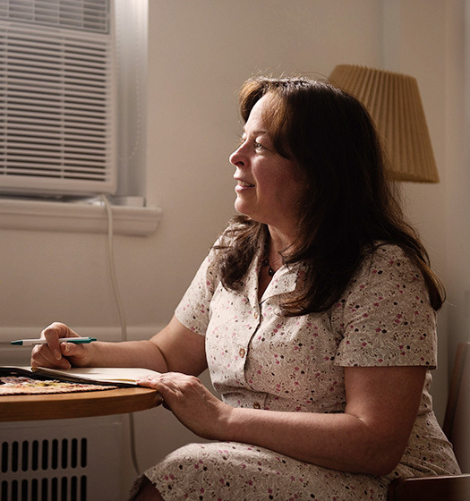 A McGill Wellness advisor sits at a table taking notes with a pen while looking out of frame.