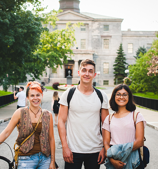 Three students standing on the pathway in front of the McCall MacBain building.